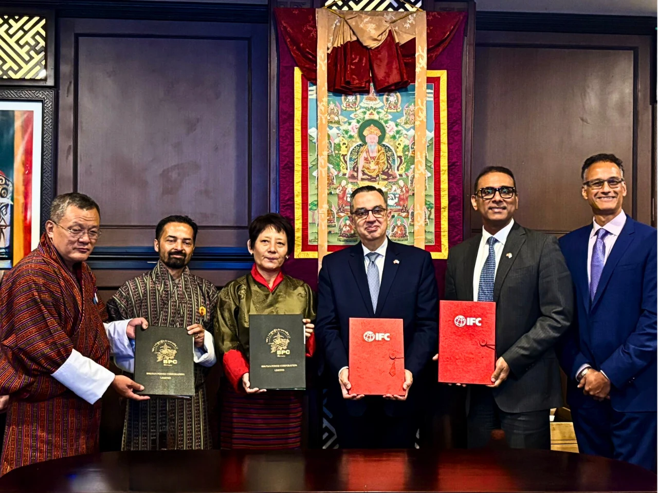 In thsi image IFC official and the bhutan nation oofical get the investment aggreement file